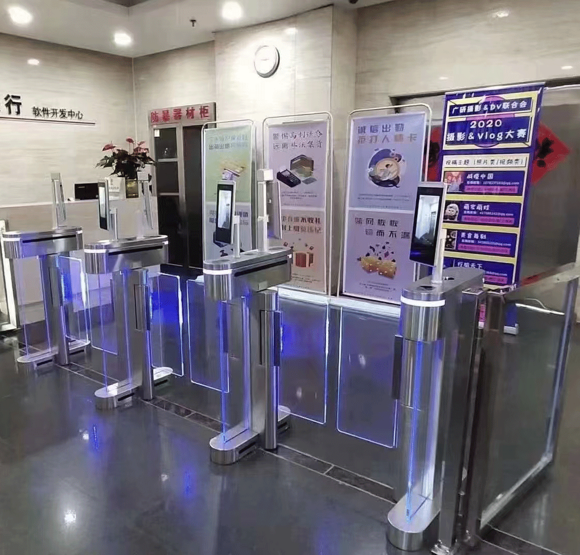 Ժամանակակից ավտոմատ տուրնիկետ թափանցիկ ապակե փեղկերով, սև-մոխրագույն կորպուսով և կանաչ LED լուսային ցուցիչով՝ մուտքի վերահսկման համակարգի համար